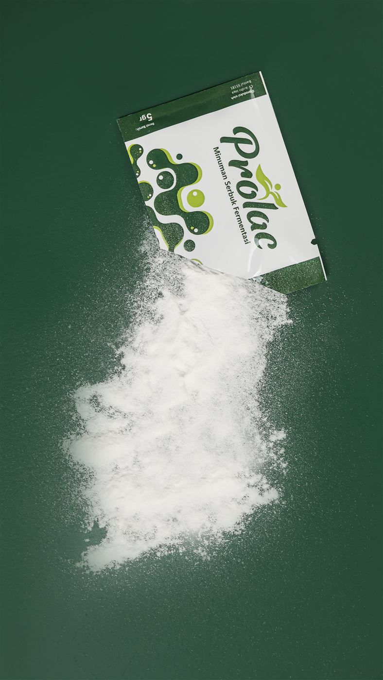 Serbuk Prolac tumpah dari sachet di atas latar hijau tua